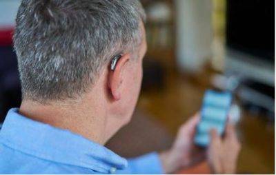 homme écoutant de la musique sur son téléphone avec un appareil auditif connecté